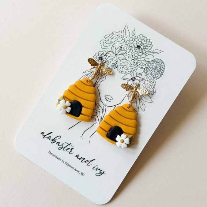 You know we can’t have flowers without the bees!

These sweet little hives feature a white flower detail and are finished with 18k gold plated bee toppers.