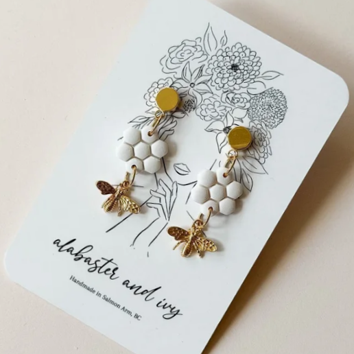 We love the bees!

These honeycomb dangles feature a gold plated bee charm and are finished with 18k gold plated circle studs.